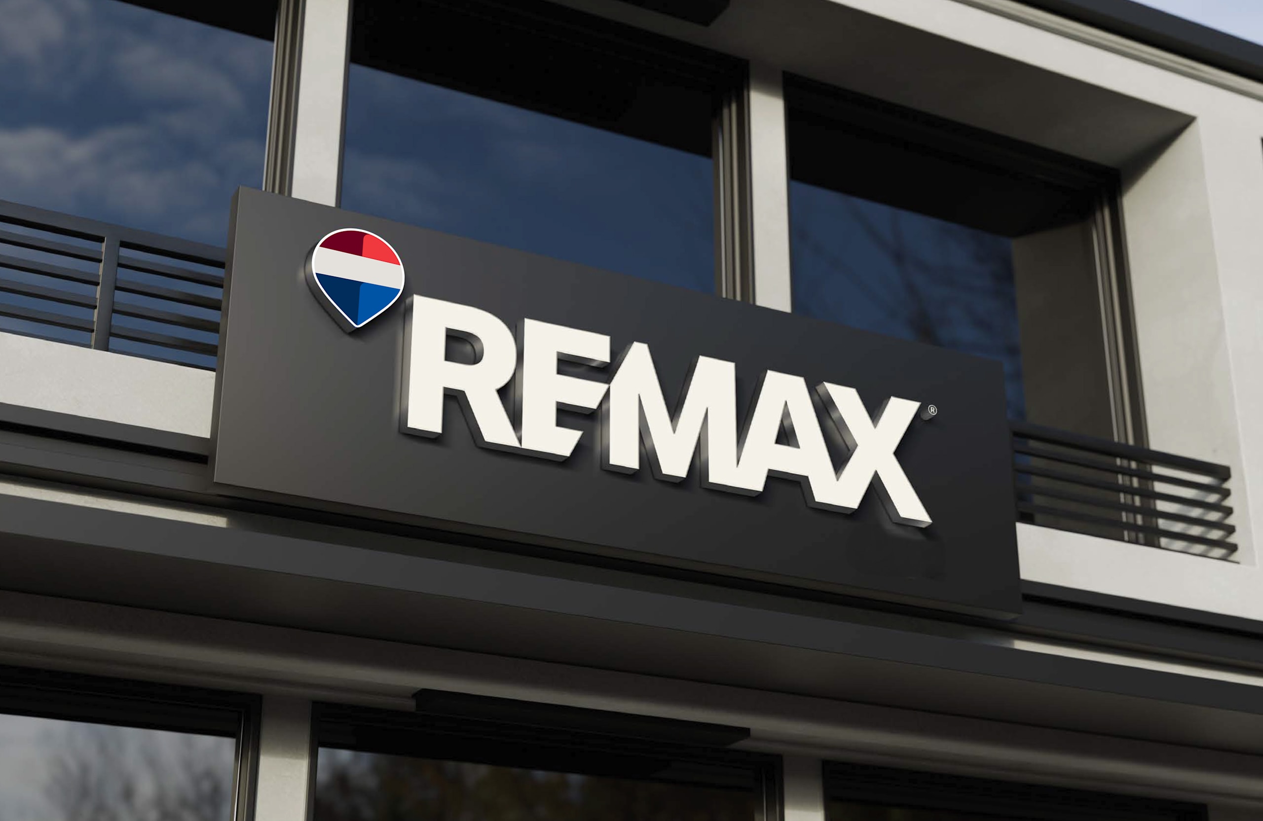 Enseigne REMAX et pin REMAX sur la façade d’une agence